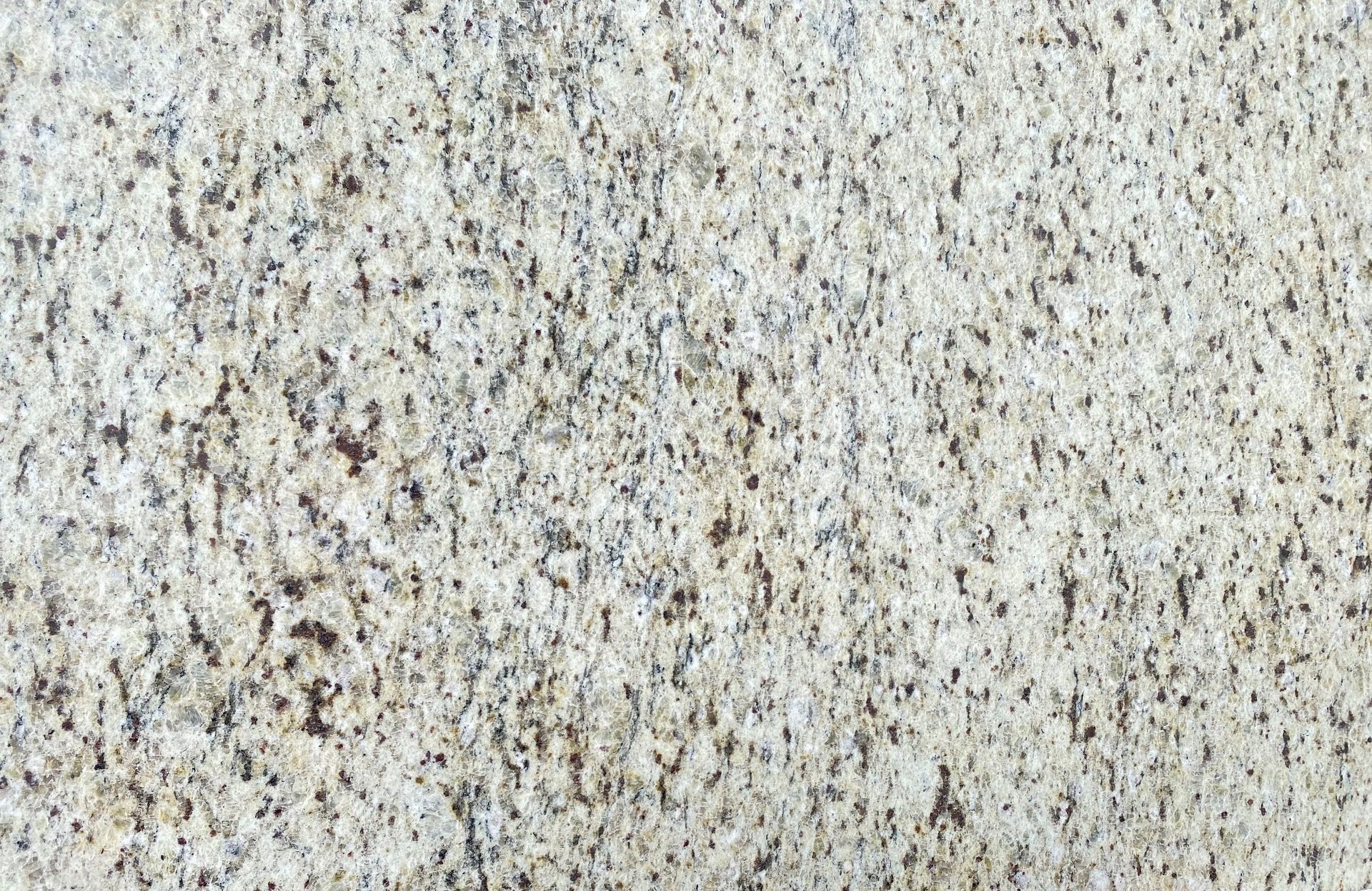Textured light gray stone surface. Small dark flecks dot the uneven surface.