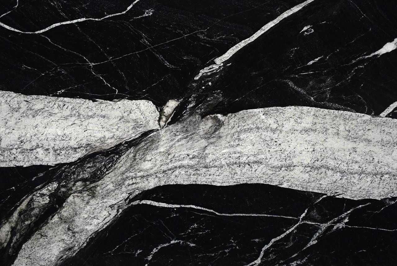 Black granite with large white streaks and fine white veins.