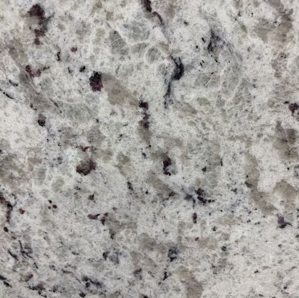 Close-up of a white granite countertop with gray and dark reddish-brown speckles and veins.