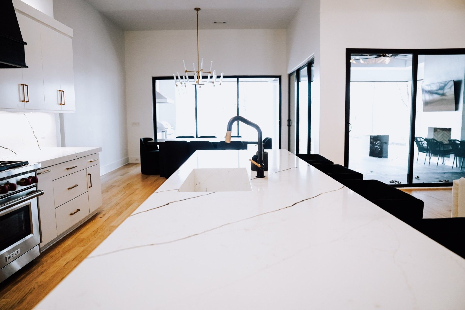 Modern kitchen with white countertops, black faucet, and large windows.