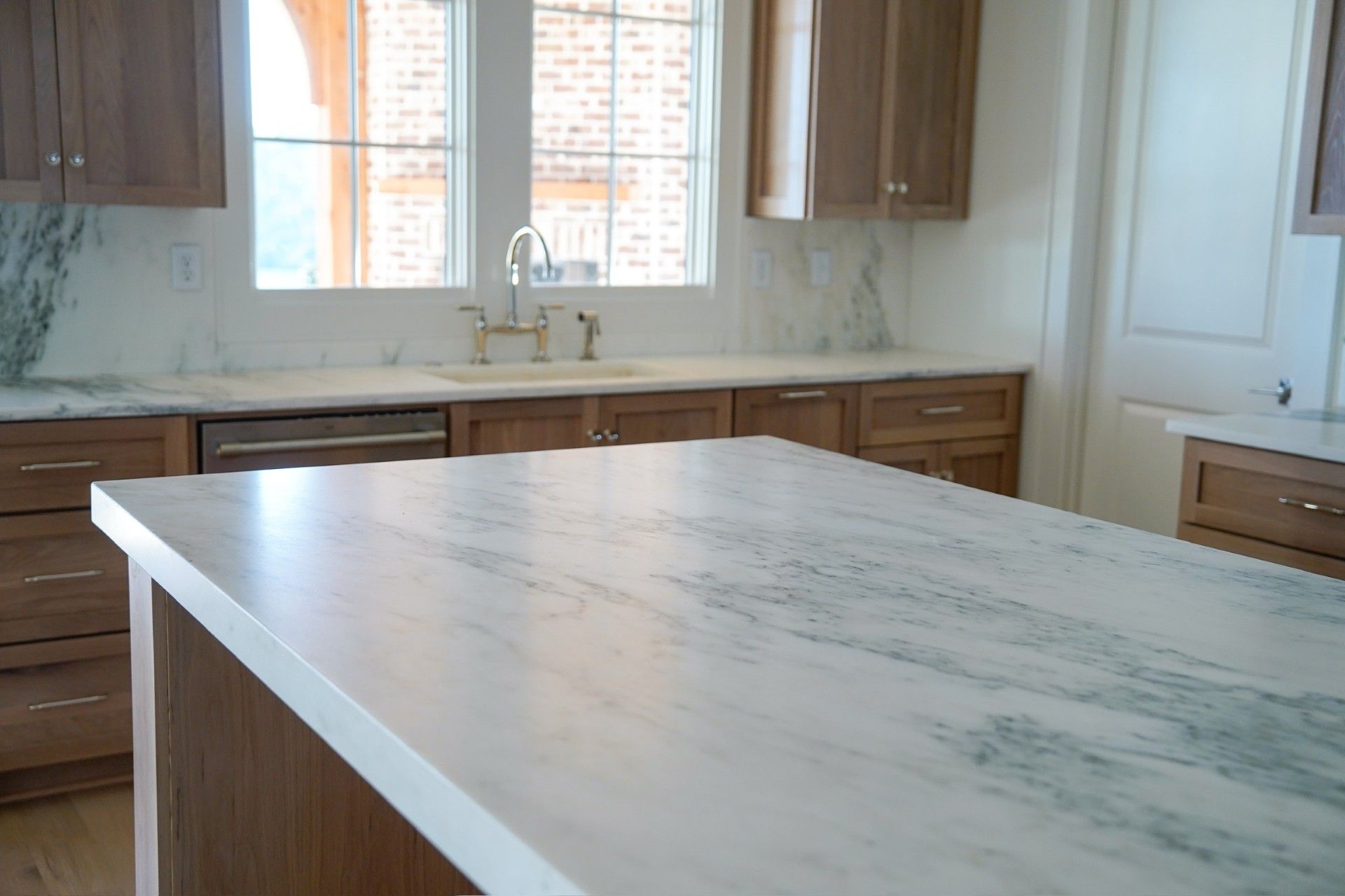 Kitchen with marble countertops, wood cabinets, and a window above a sink.