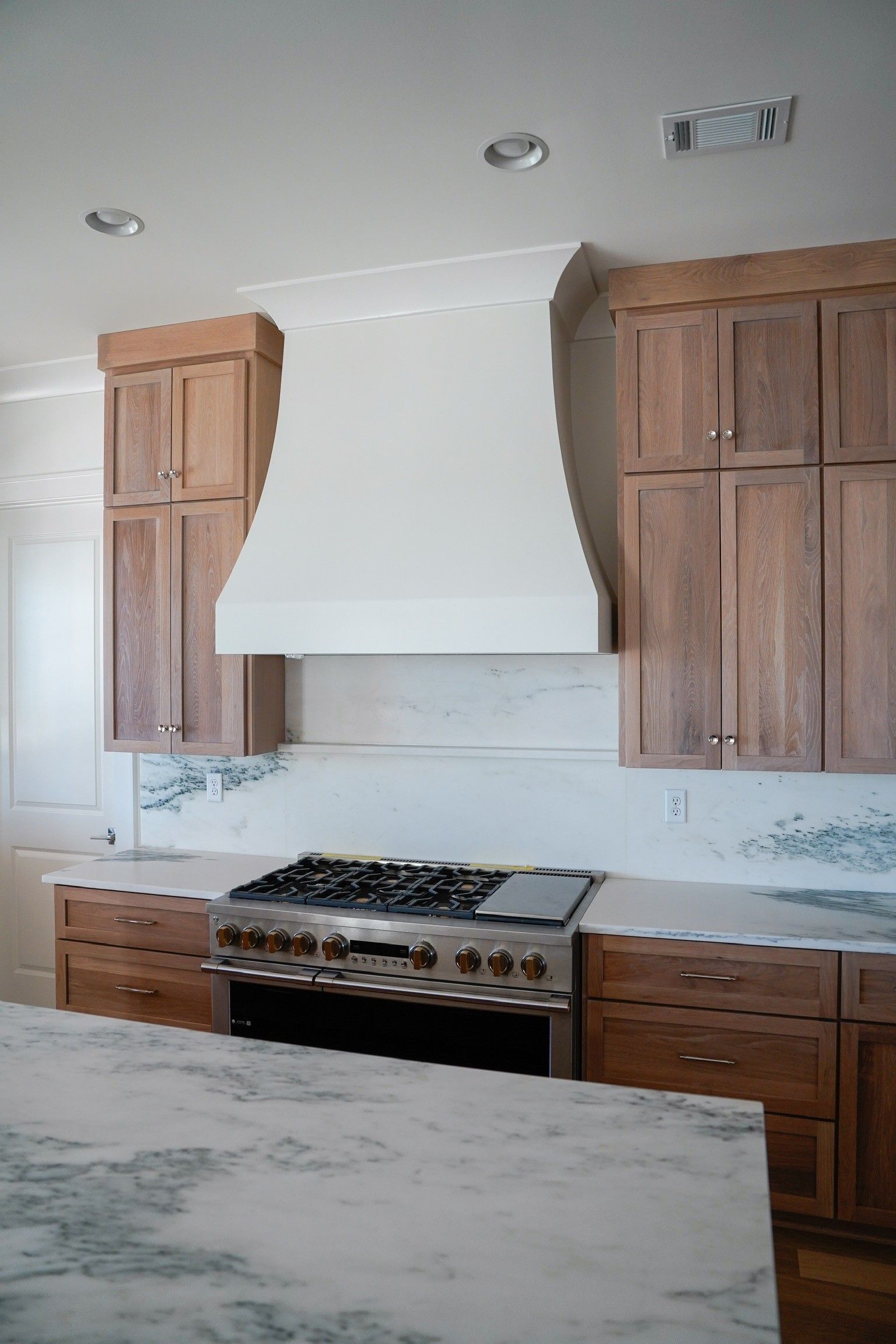 Kitchen with wooden cabinets, stainless steel range, and white range hood.