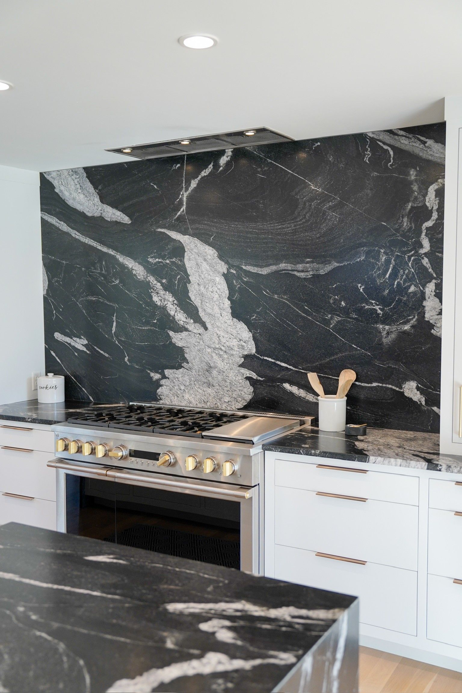 Modern kitchen with a black granite backsplash and range, white cabinets.