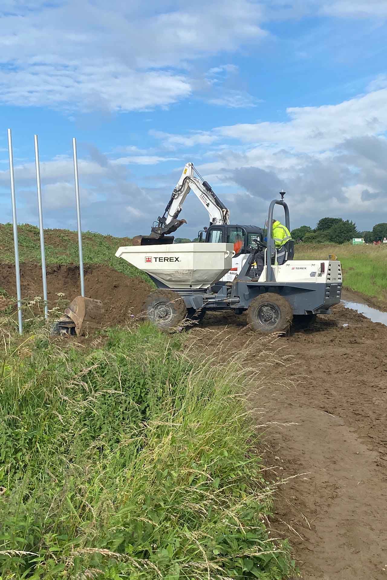 a DHS Plant Hire Terex swivel tip dumper  tipping soil in a field