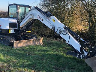 A DHS Plant Hire Bobcat mini excavator removing turf in a field