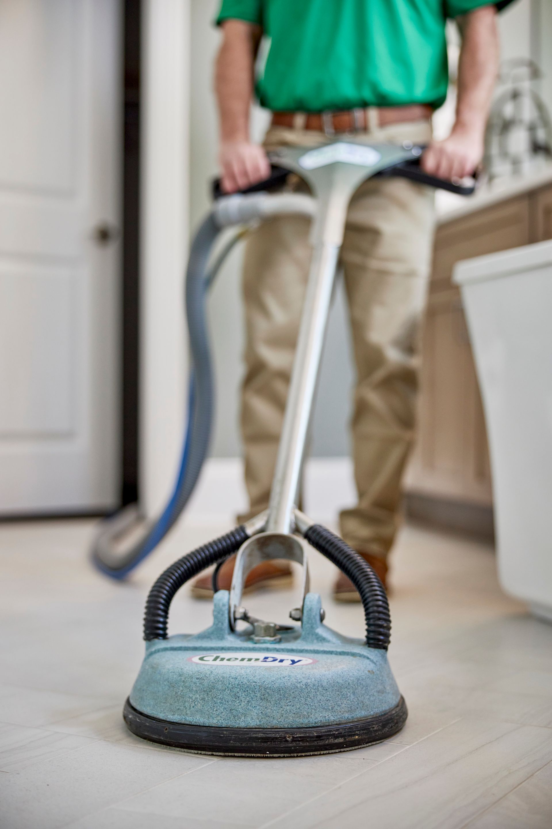 Person using a floor cleaning machine in a bathroom. The machine is gray and black.