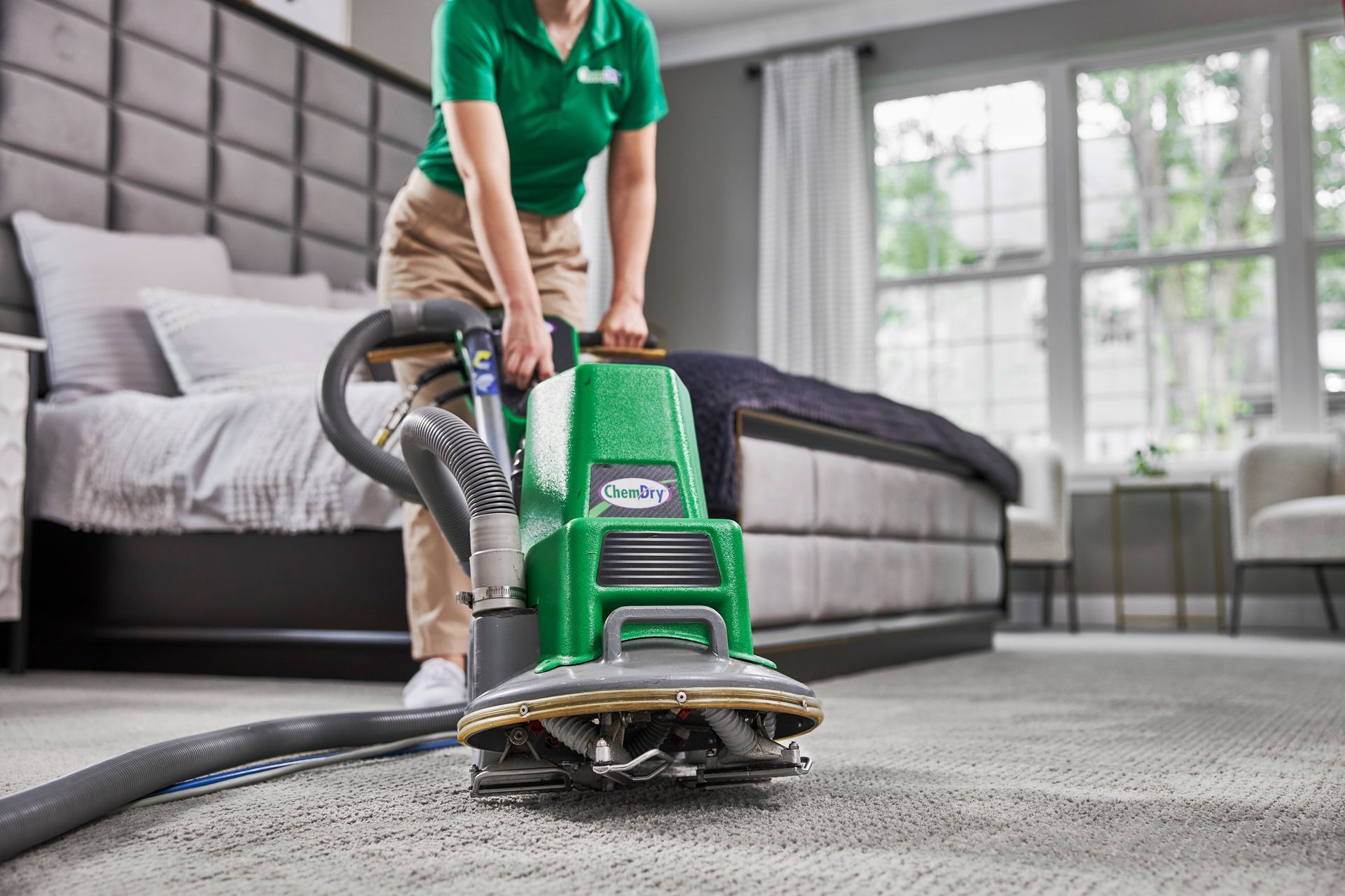 Person cleaning carpet with a green machine in a bedroom.