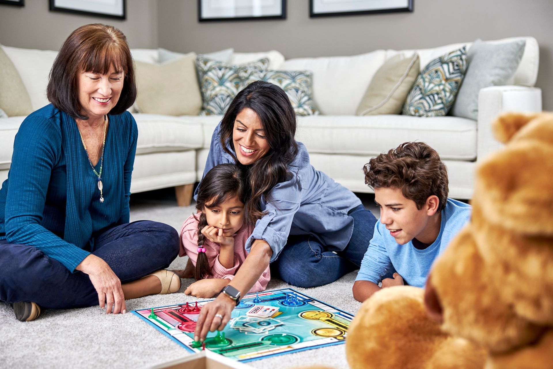Family playing a board game on a carpeted floor in a living room.