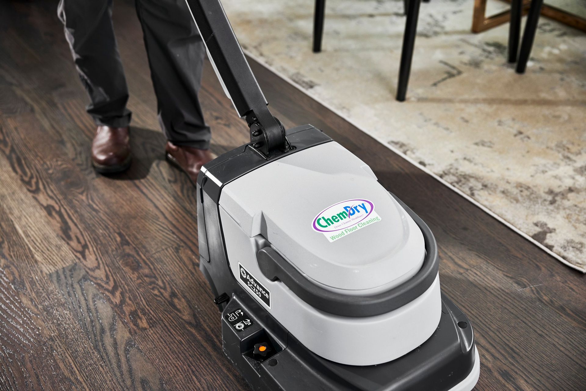 Person operating a floor cleaning machine on hardwood. Machine has the