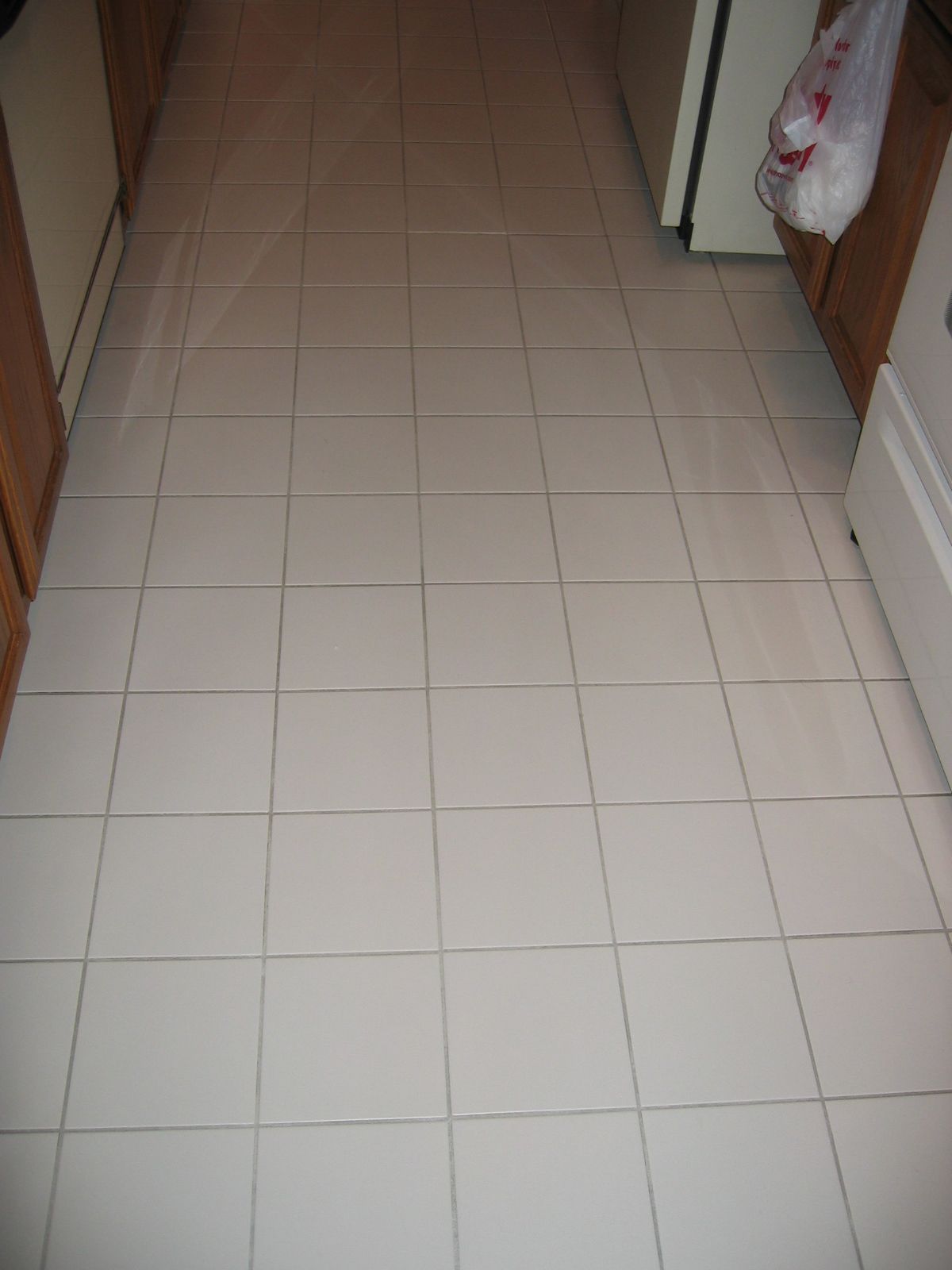 White tiled kitchen floor, with visible grout lines and cabinetry.