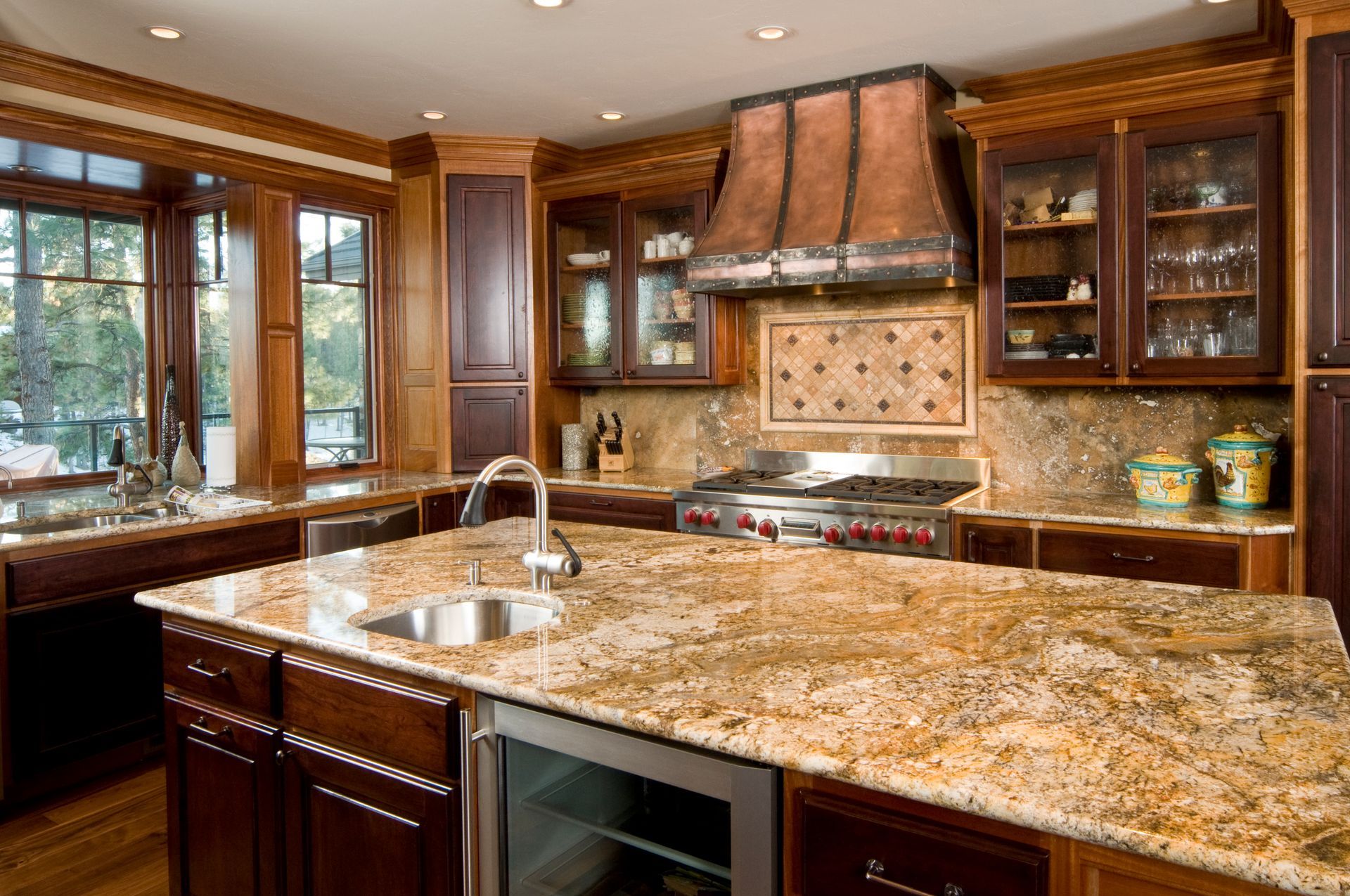 Luxury kitchen with granite countertops, dark wood cabinets, and copper range hood.