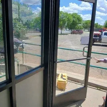 Open glass door looking onto a parking lot, with a yellow caution sign on the floor.