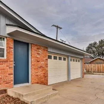 Brick house exterior with blue door, two-car garage, and concrete driveway