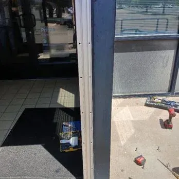 Store entrance with open door, tiled floor, and scattered items outside on the sidewalk.