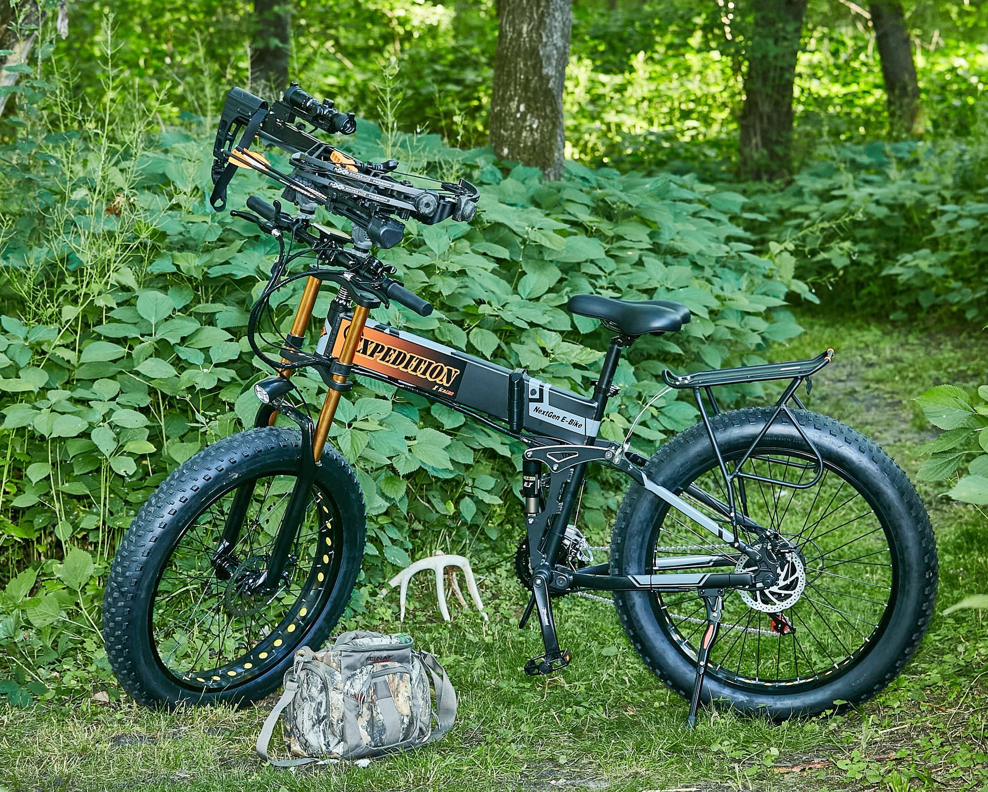 A bicycle is parked in the grass in the woods.
