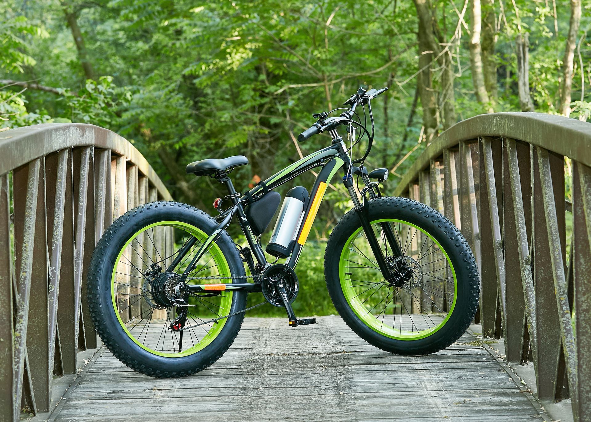 An electric bicycle is parked on a wooden bridge in the woods.