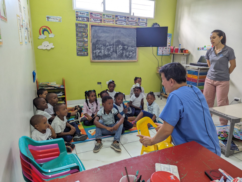 Teacher leading a seated group lesson in a colorful classroom with young children and learning materials