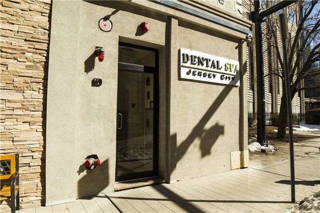 The entrance to the Dental Spa in Jersey City, featuring a beige stucco wall, a glass door, and a prominent sign.