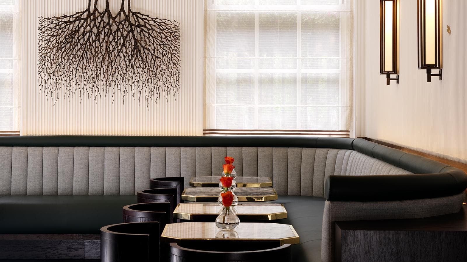 Restaurant booth with upholstered seating, small tables, and art.