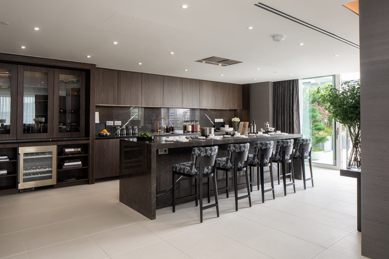 Modern kitchen with dark wood cabinetry, large island with seating, and wine fridge.