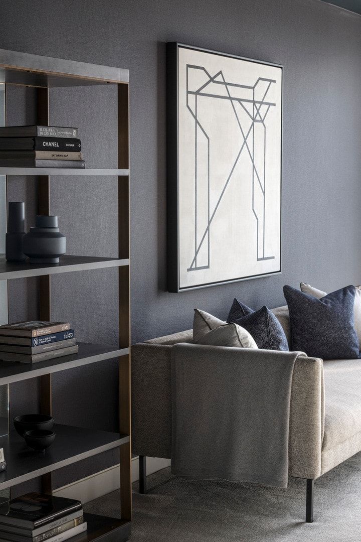 Living room with gray walls, shelves, sofa, and abstract art.