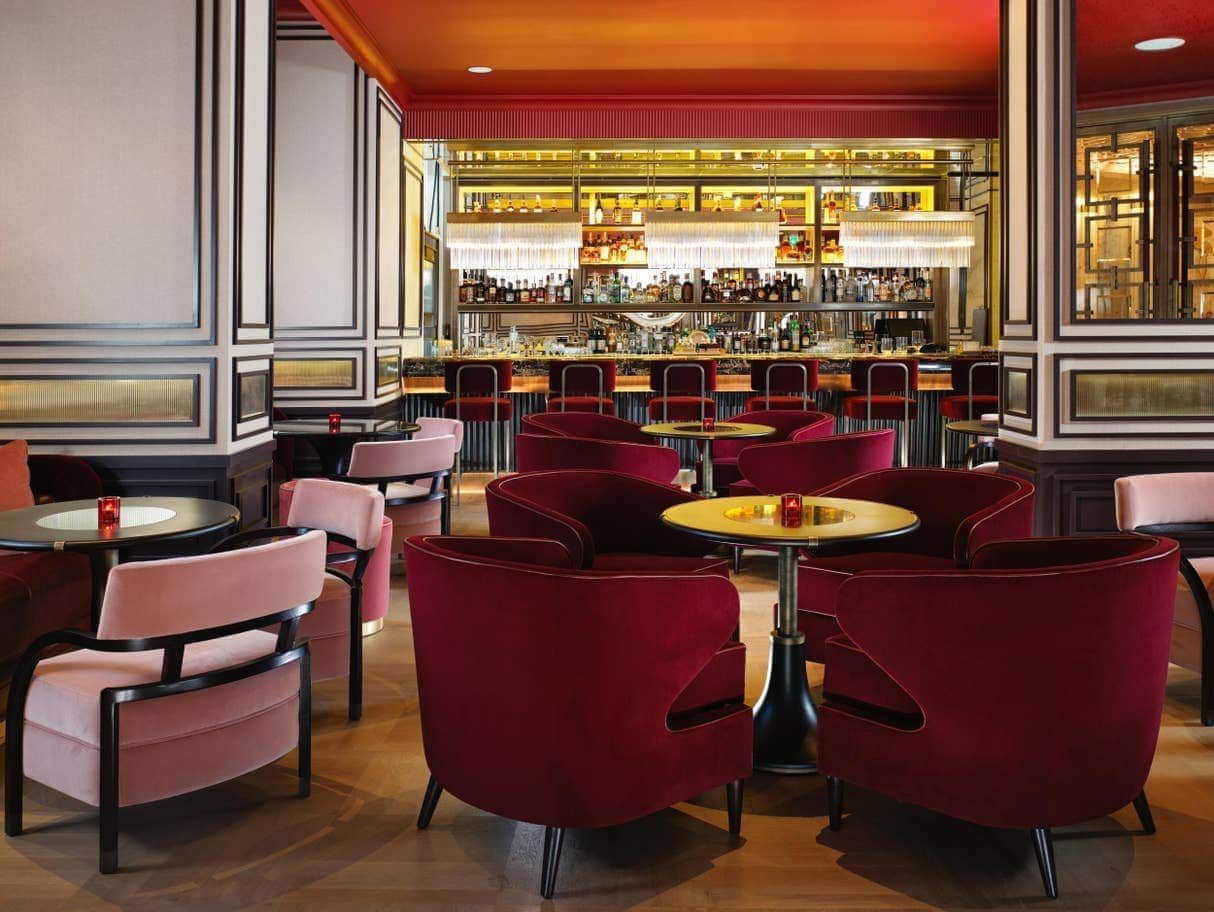 Interior bar with red and pink seating, gold accents, and a well-stocked bar in the background.