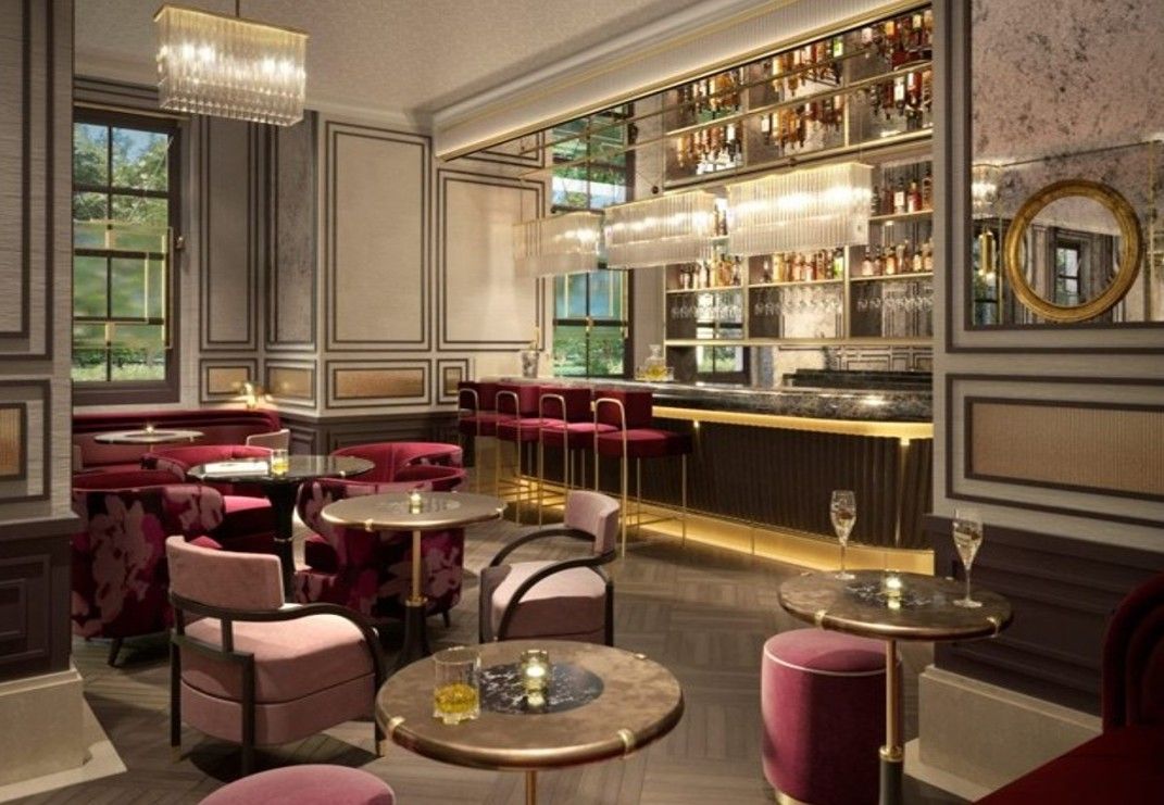 Elegant bar interior: red velvet seating, marble tables, and a well-stocked bar with mirrored back.