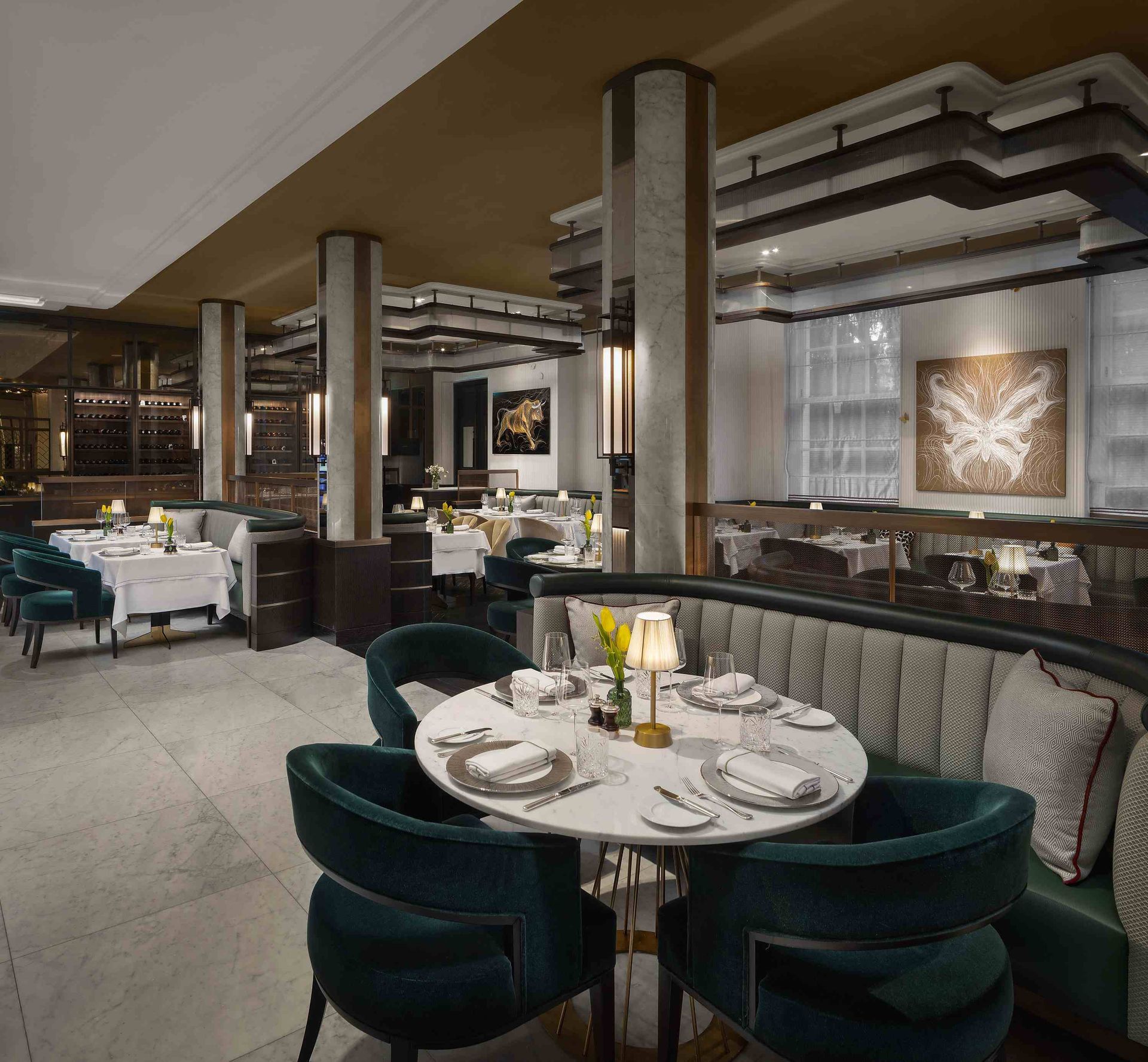 Elegant restaurant interior with round table, green chairs, and plush booth.