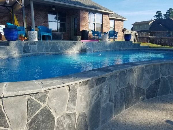 A large swimming pool in front of a brick house