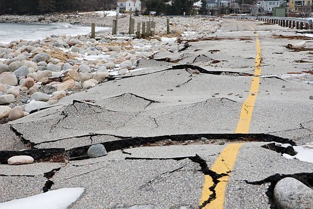 A cracked road with a yellow line going through it