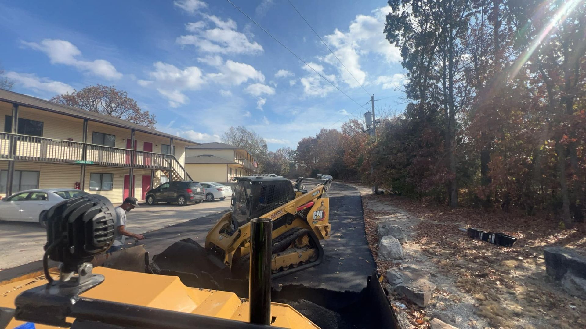 A bulldozer is moving dirt on a road in front of a building.