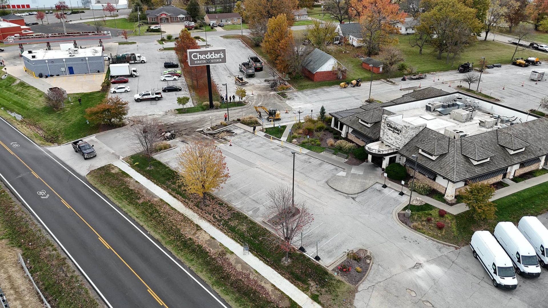 An aerial view of a parking lot next to a road and a building.