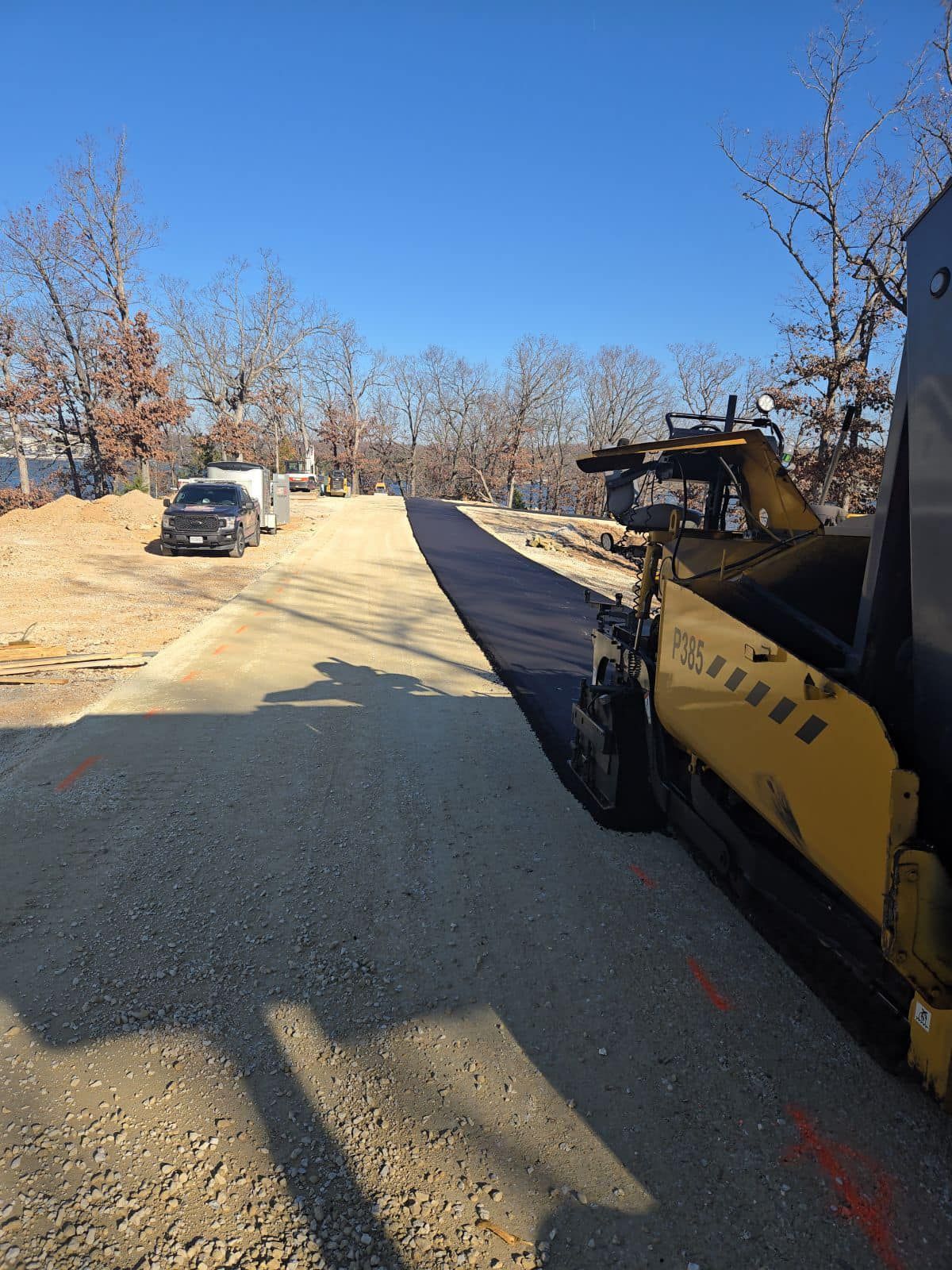A yellow asphalt roller is sitting on the side of a road.