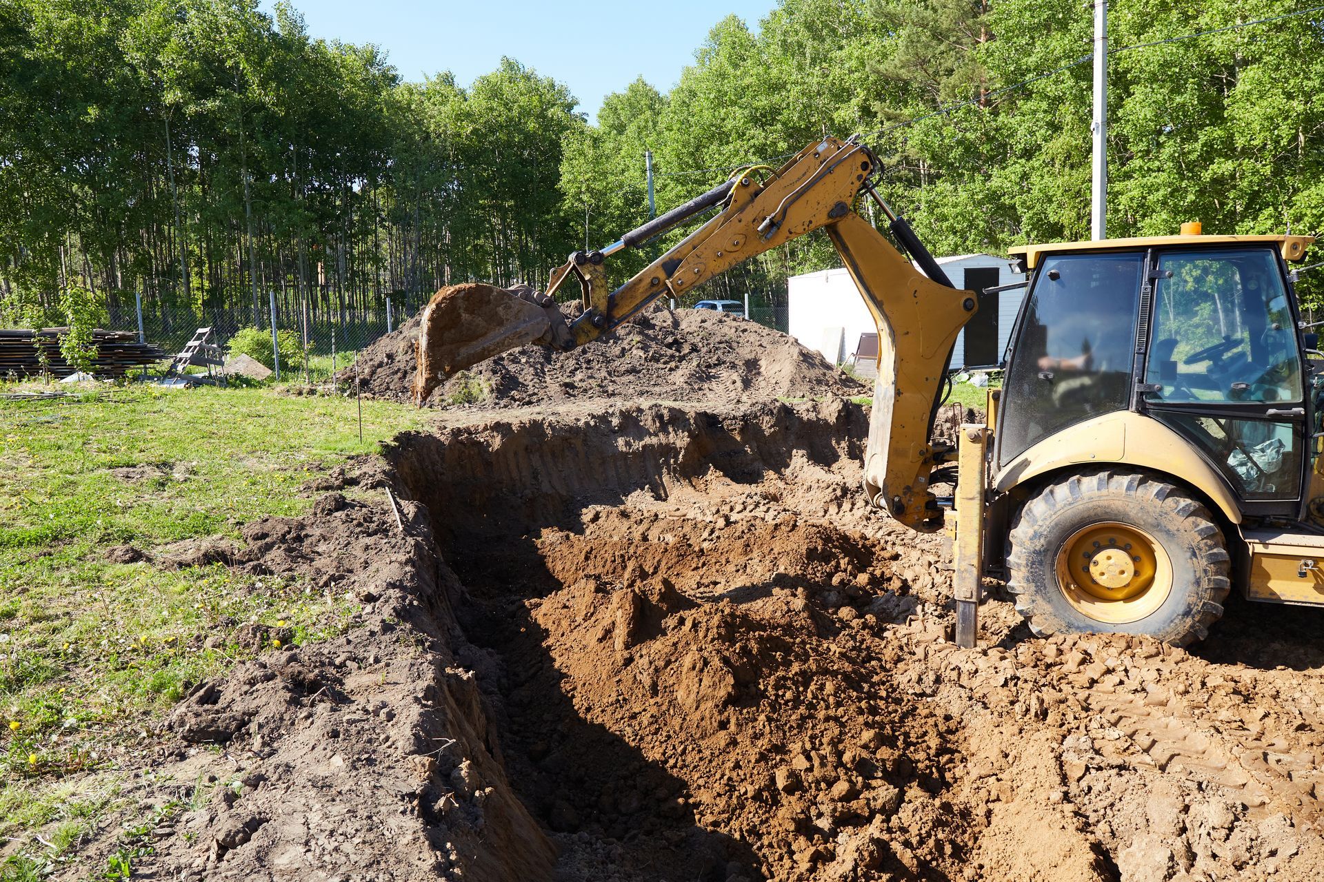 Excavating contractor operating a backhoe to dig a foundation trench on a construction site