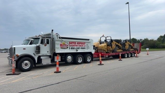 A dump truck with a trailer attached to it is parked in a parking lot.