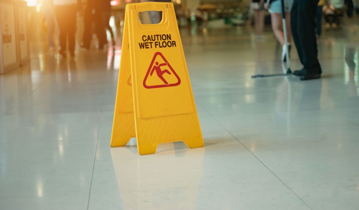 A yellow caution wet floor sign is sitting on a tiled floor.