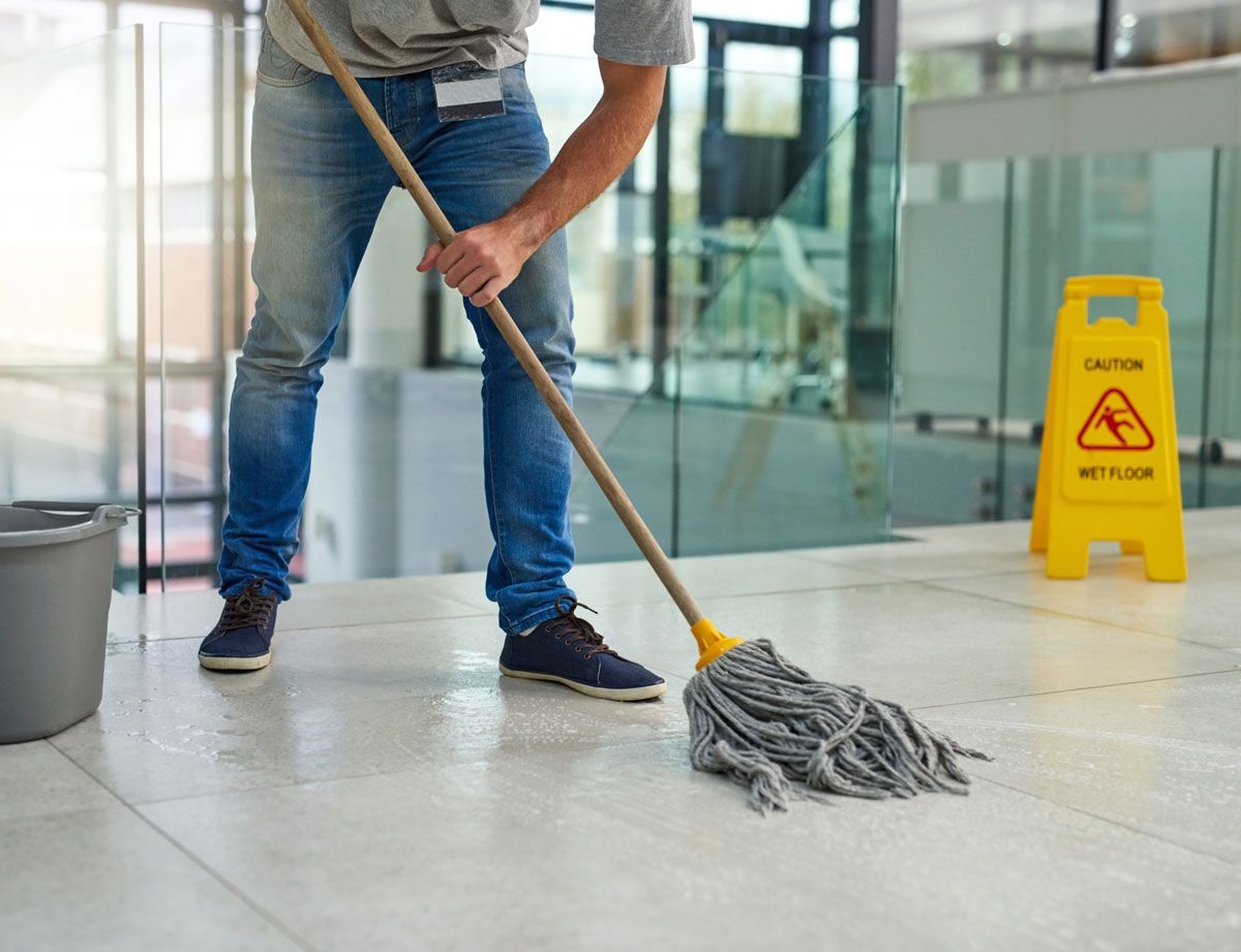 A man is cleaning the floor with a mop and bucket.