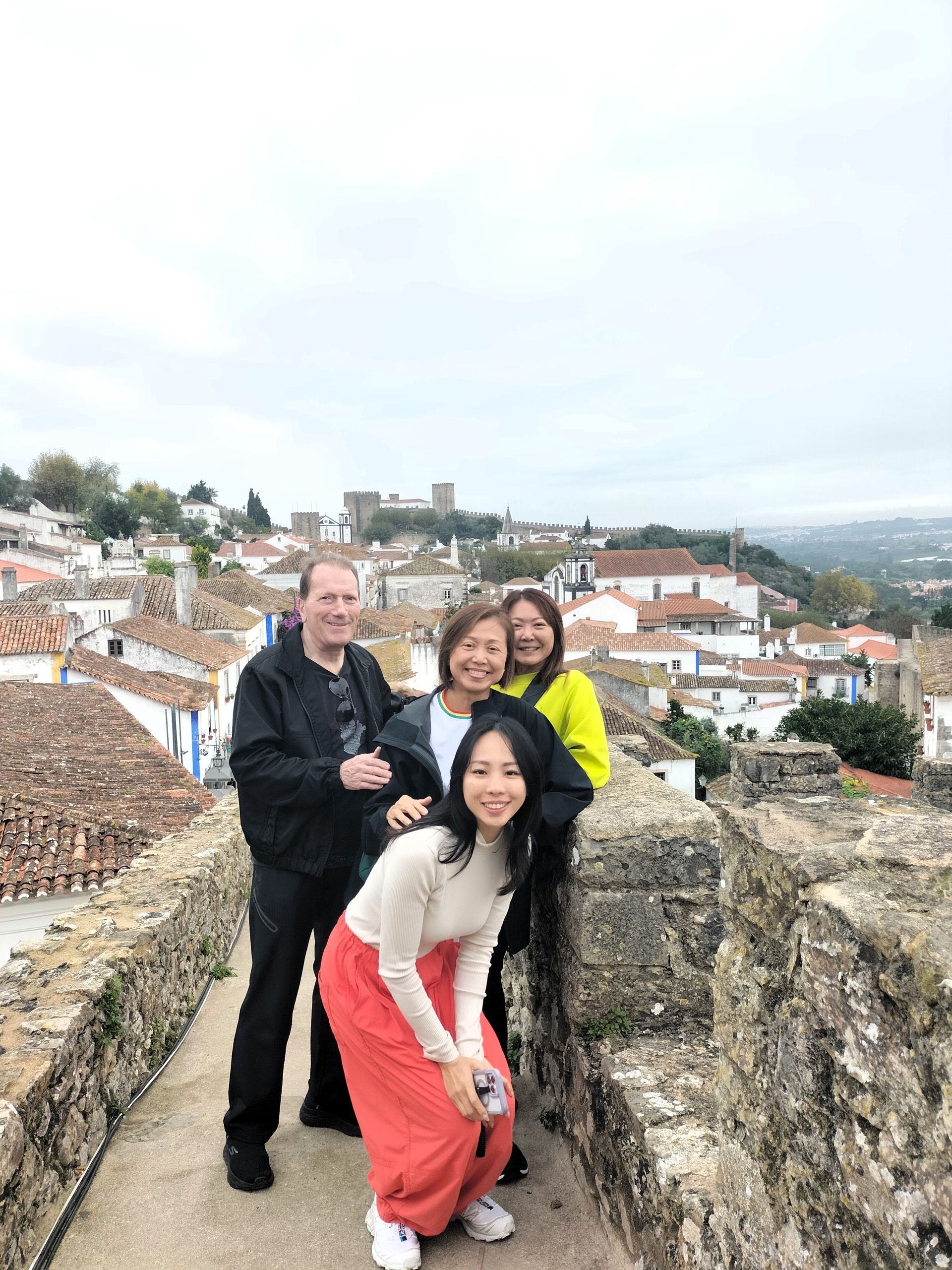 A group of happy travelers on top of the walls of the medieval town of รbidos in Portugal during a guided tour from Lisbon,