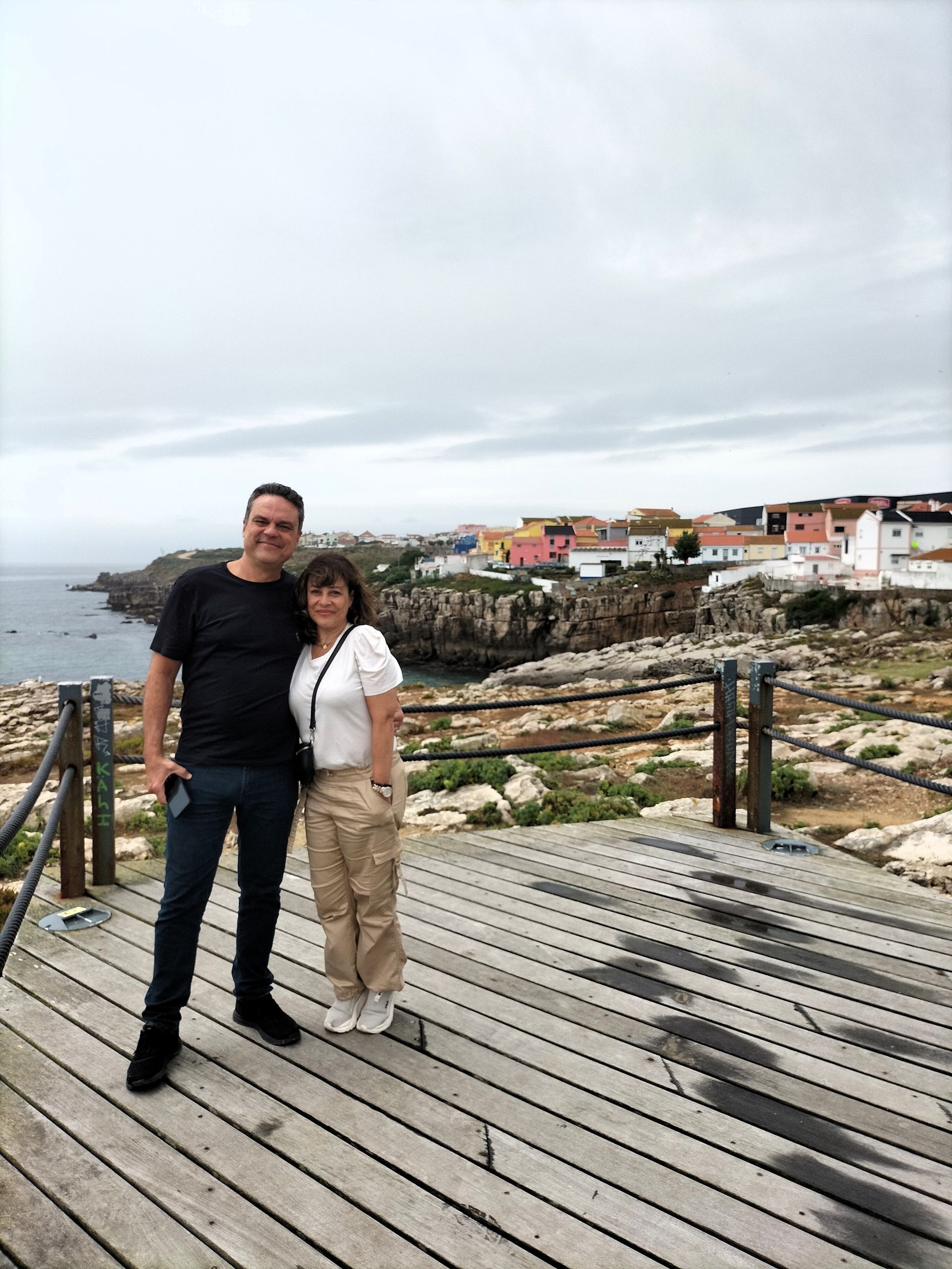 Travelers on the cliffs by the Atlantic with Peniche's typical neighborhood in the background during a tour from Lisbon.