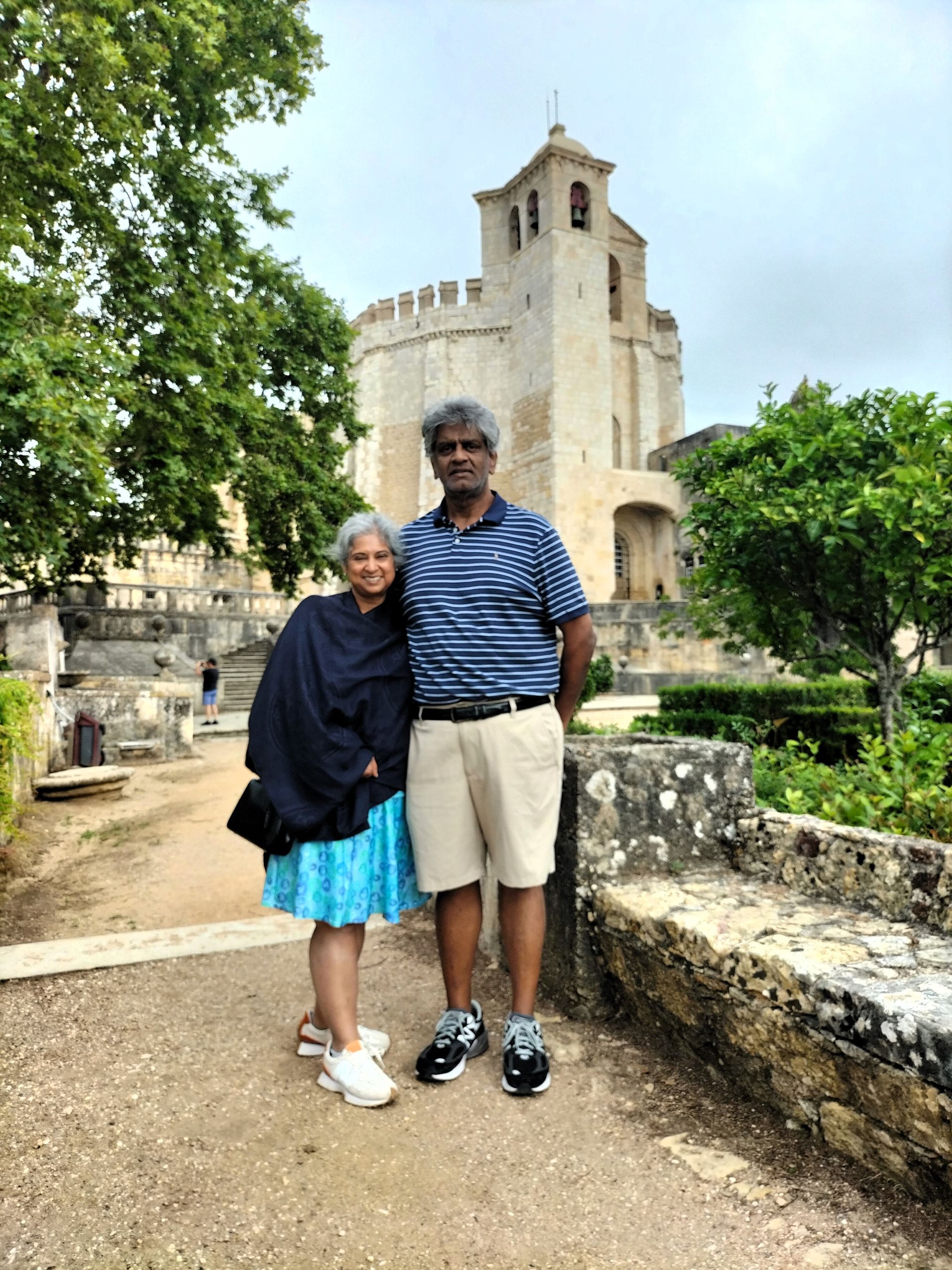 A couple of happy travelers with the Templar Convent of Christ in Tomar in the background during a private tour from Lisbon.
