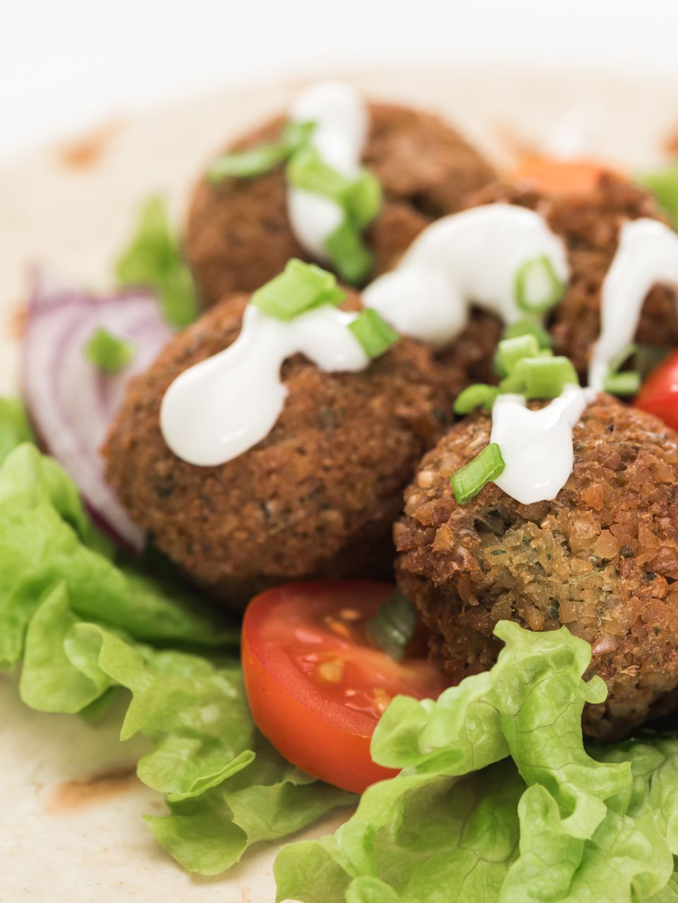 a close up of falafel on a tortilla with lettuce and tomatoes