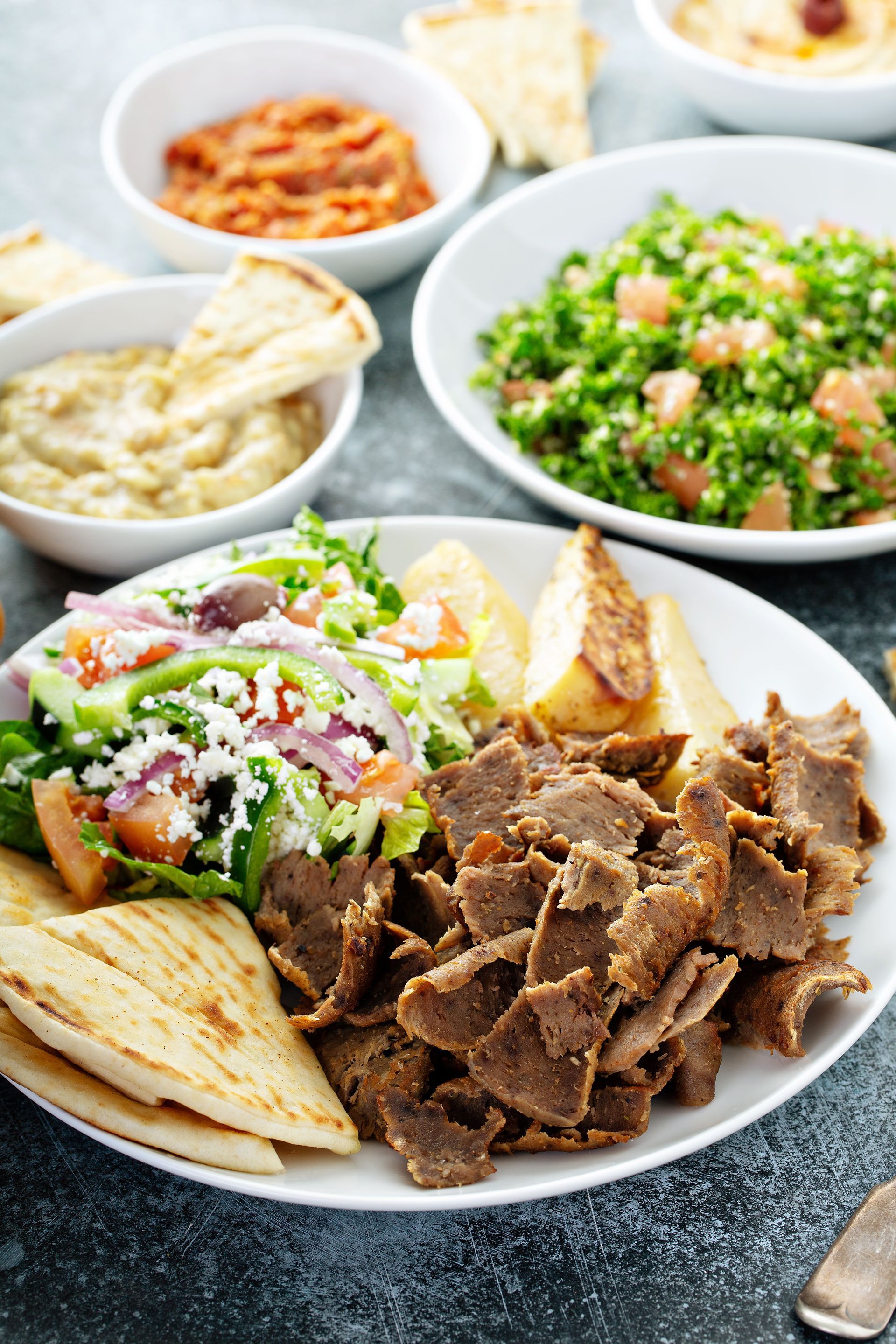 a plate of gyros with pita bread and a salad on a table .