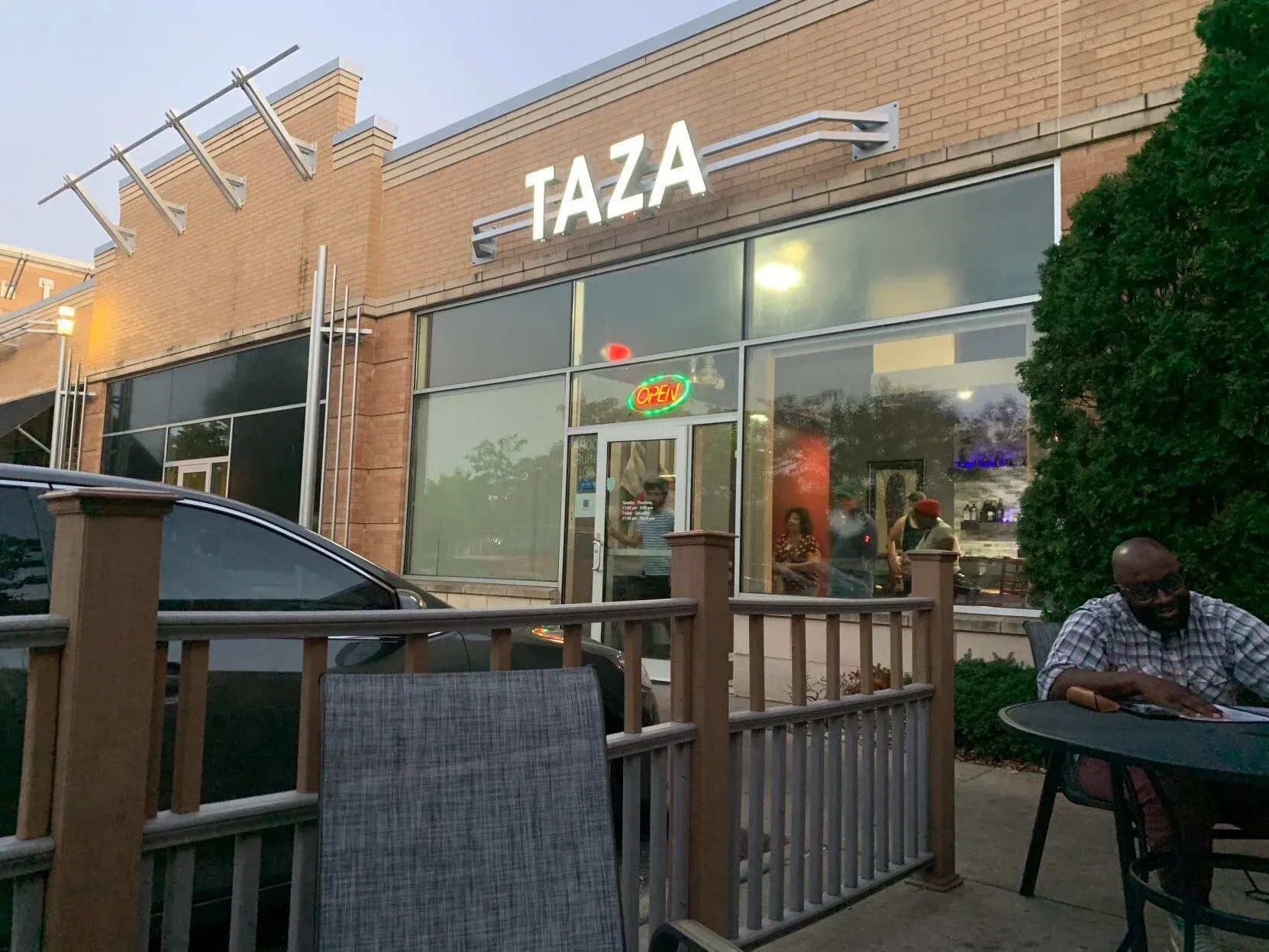 a man is sitting at a table outside of a restaurant called taza