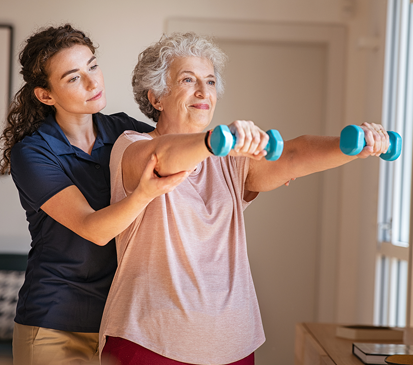 Woman assists senior exercising with dumbbells.
