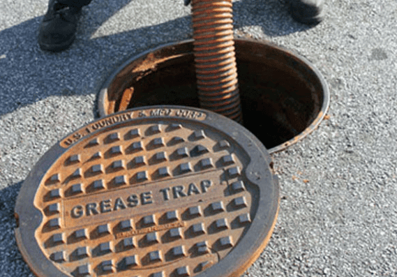 Open grease trap manhole with round metal cover on pavement — Wee R Pumping In Glenorchy, TAS