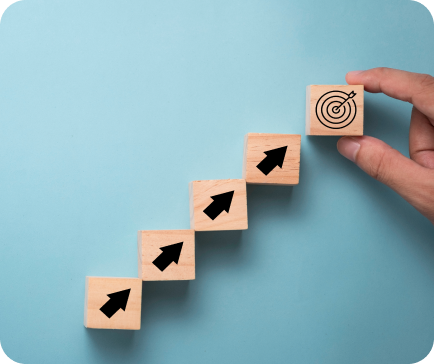 Hand placing target block on upward-arrowed blocks, symbolizing goal achievement on blue.