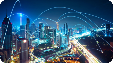 Night cityscape with glowing blue lines connecting buildings, representing network connectivity.