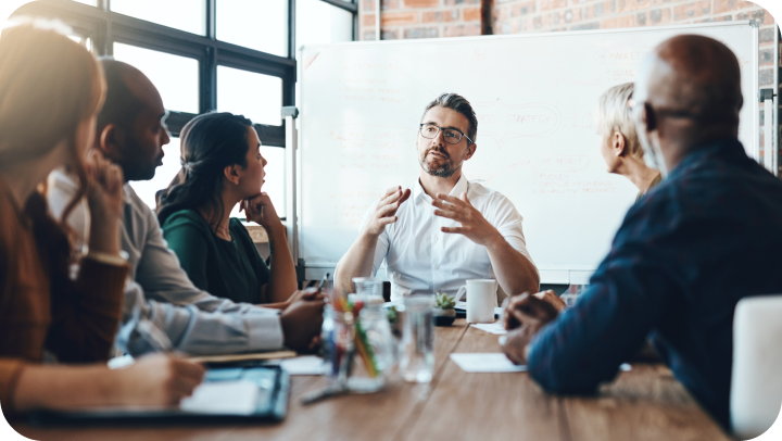 Business meeting in a modern office. A group of diverse colleagues are gathered around a table, discussing ideas.