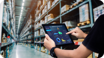 Person using tablet in warehouse, reviewing inventory management dashboard.