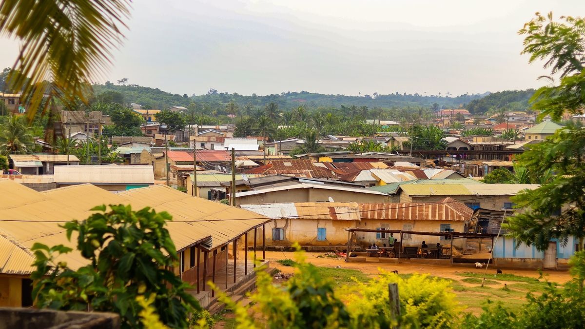 A view of a town in a tropical region with many buildings and trees under an overcast sky.